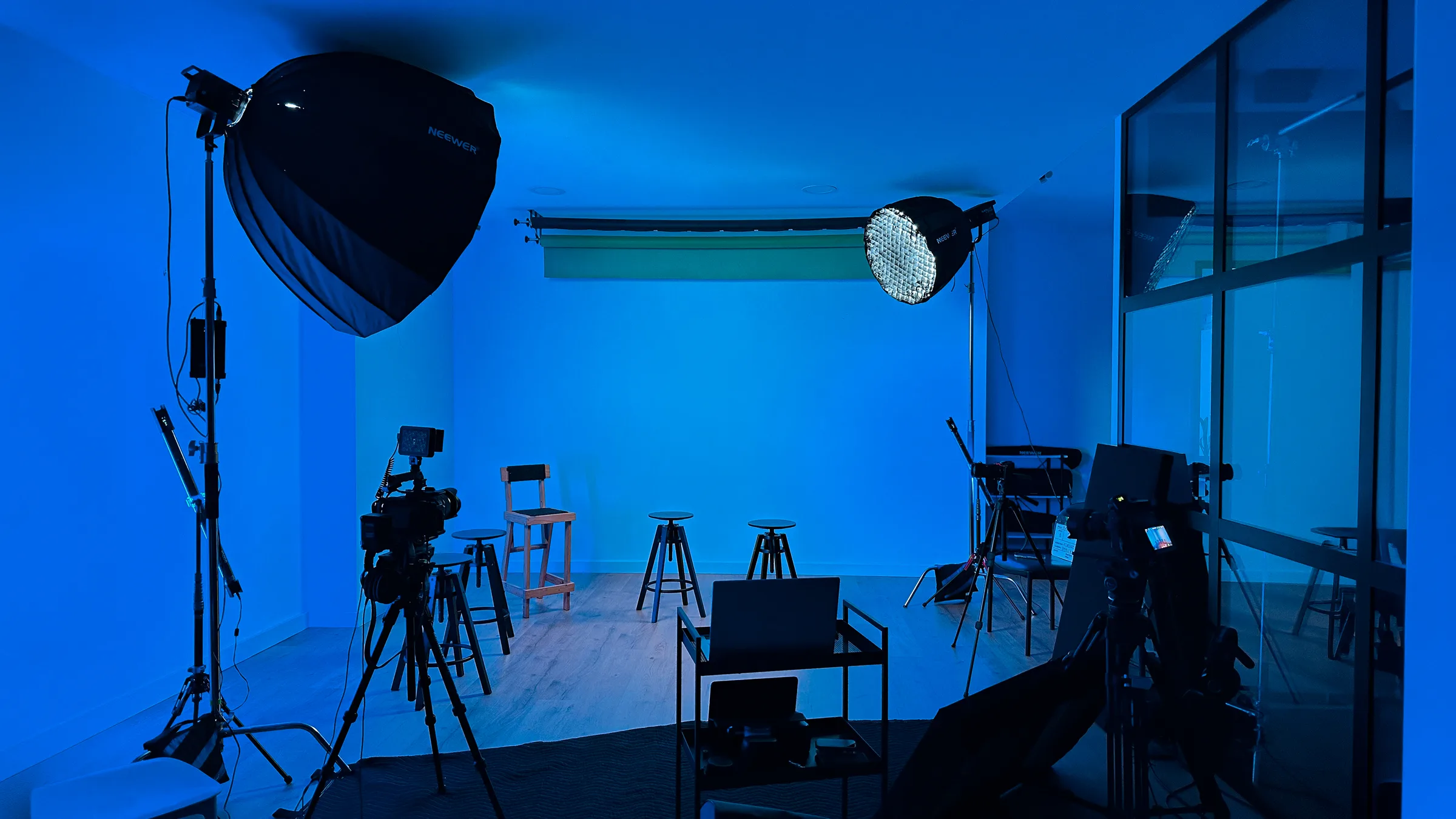 Setup de fotografia e vídeo no estúdio AIRLUSO: softbox Neewer, painel LED redondo, câmaras em tripé, ciclorama branco ao fundo.